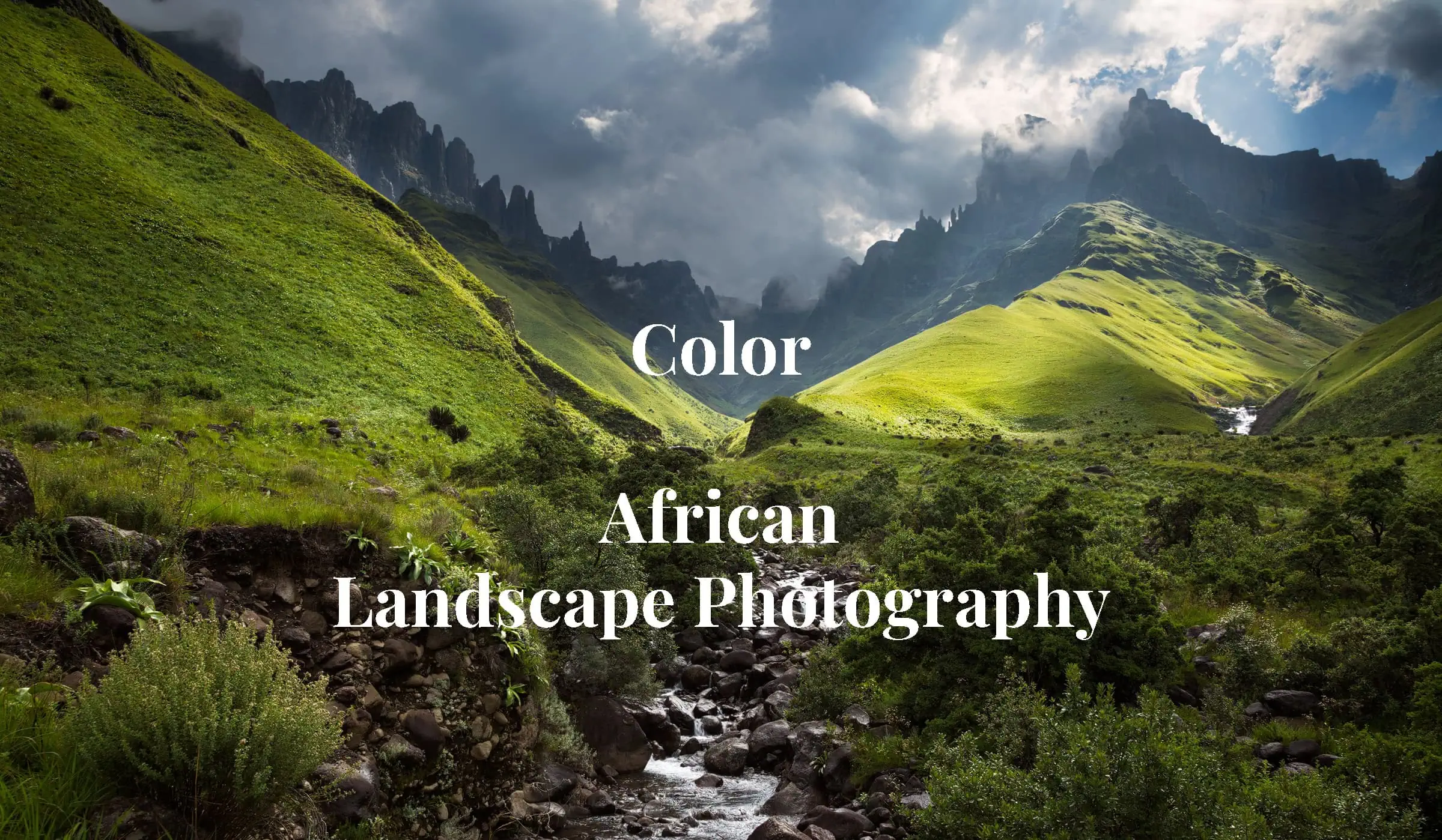 Fangs Valley - Rocky sharp cliffs of Fangs Pass in Drakensberg in background with green grassy slopes and river in foreground, in fine art African landscape photography by Rudi van den Heever