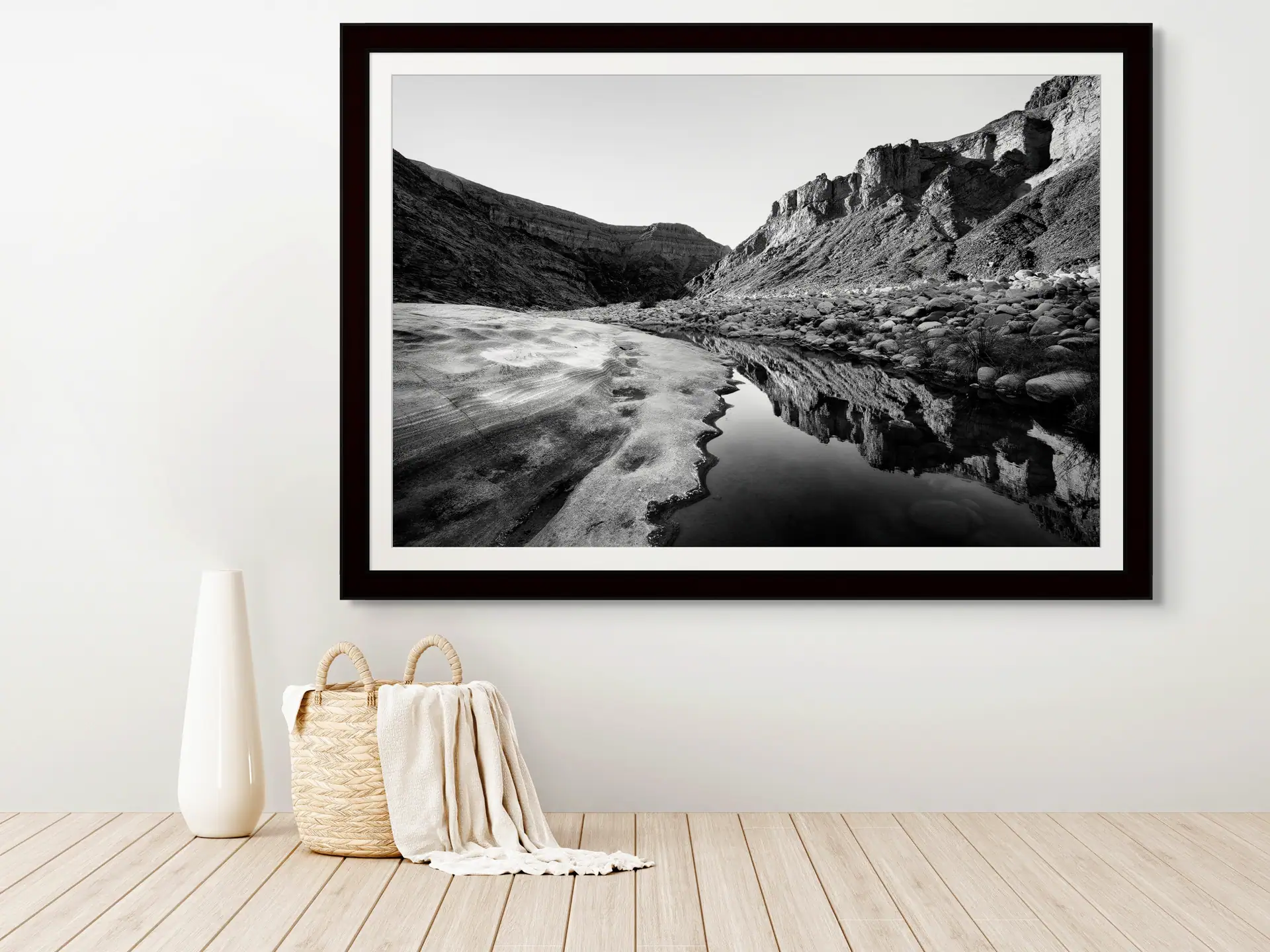 Framed black and white fine art landscape print of Fish River Canyon with reflection in river at bottom of the canyon, hanging on a living room wall for home decor inspiration.